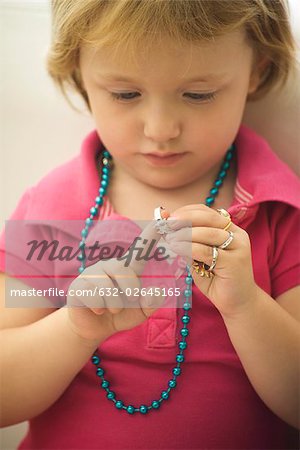 Little girl playing with costume jewelry, putting on ring