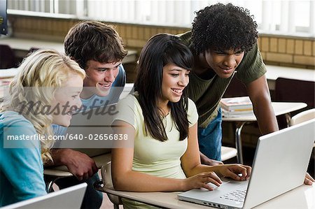 Vier Studenten drängten sich um einen Notebook-Computer.