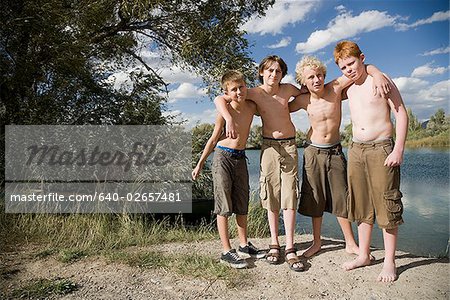 quatre jeunes garçons jouant près d'un lac.