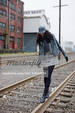 Frau zu Fuß auf Eisenbahnschienen im städtischen Gewerbegebiet, Portland, Oregon, USA