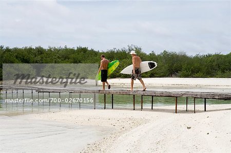Surfeurs traverser la passerelle à poulets Surf Break, North Male Atoll, Maldives