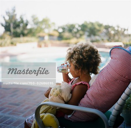 Fille prenant un verre au bord de piscine