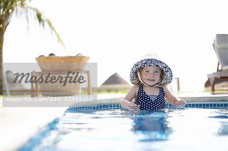 Fille portant le chapeau de soleil debout dans la piscine, Cancun, Mexique