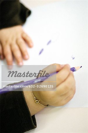 Child drawing with colored pencil, cropped view of hands