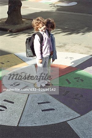 Little girls standing on hopscotch grid, portrait