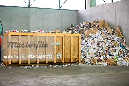 Paper and cardboard piled up beside dumpster in recycling center