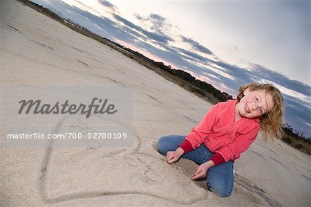 Mädchen und Herz im Sand am Strand gezeichnet
