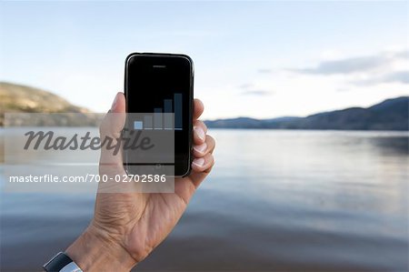 Man Holding iPhone near Lake