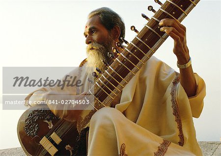 Elderly man playing a sitar by the Ganges (Ganga) River, Varanasi (Benares), Uttar Pradesh State, India