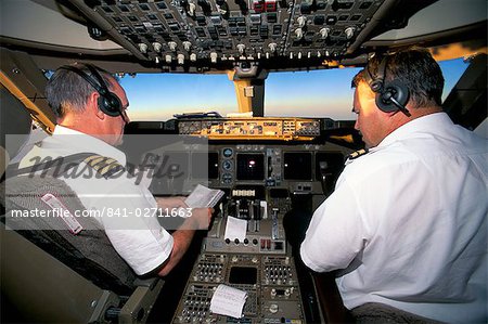 Pilots on flight deck of Jumbo Boeing 747 of Air New Zealand with sunrise ahead