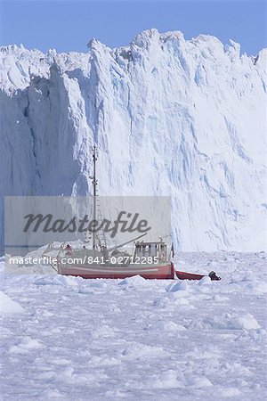 Red wooden boat crossing the ice in front of the Eqi Glacier, near Ilulissat, Greenland, Polar Regions