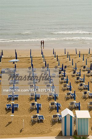 Quiet beach with beach hut, one umbrella open, and two people at waters edge, Jesolo, Veneto, Italy, Europe