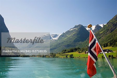 Sailing on the green lake and Norwegian flag, Olden, Fjordland, Norway, Scandinavia, Europe