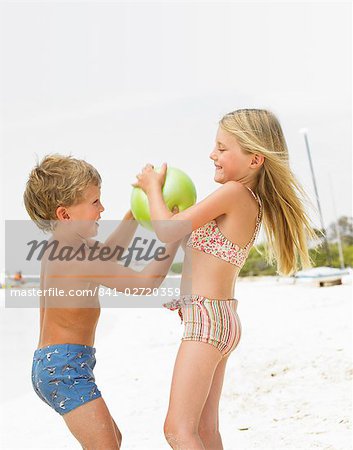 Jungen und Mädchen (6-8) am Strand spielen mit ball