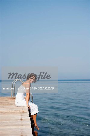 Frau sitzt auf einem pier
