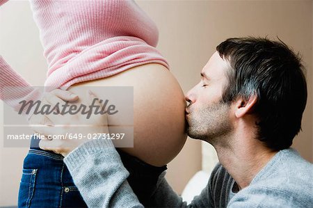 Man kissing woman's pregnant stomach