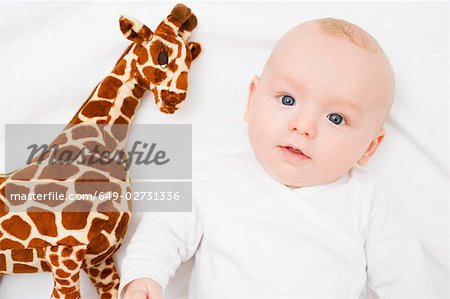 Bébé pose à côté d'une girafe en peluche
