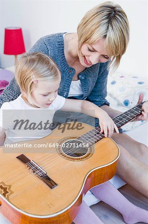 Girl and woman playing with a guitar