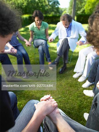 Circle of people in rehab, holding hands
