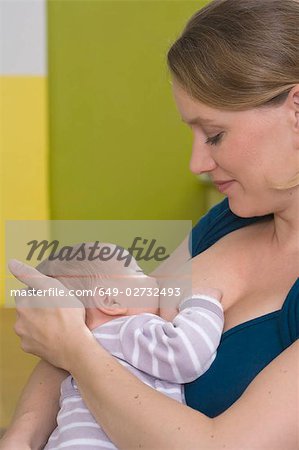 Young woman breastfeeding baby,  happy