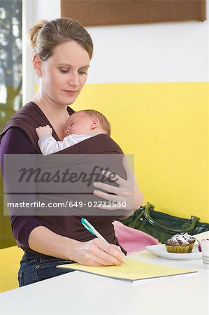 Mother with baby in baby sling,  writing