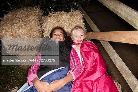 Girls in sleeping bags on haybales