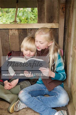 Girl reading story to young boy