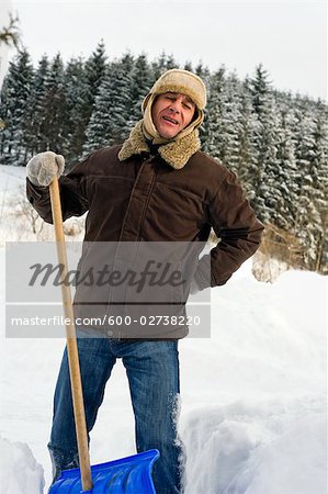 L'homme souffrant dos douleur tandis que pelleter de la neige, Hof bei Salzburg, Land de Salzbourg, Autriche