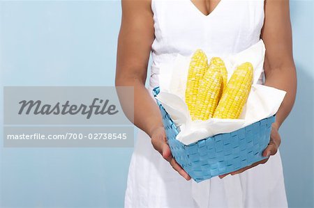Femme tenant panier d'épis de maïs