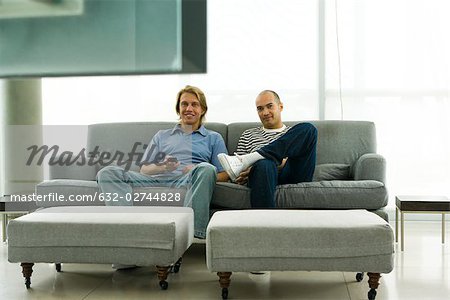 Deux hommes assis sur le canapé à regarder la télévision