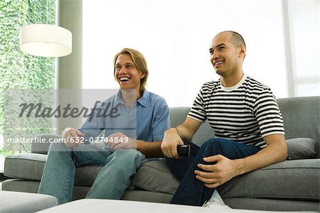 Two men watching TV on sofa
