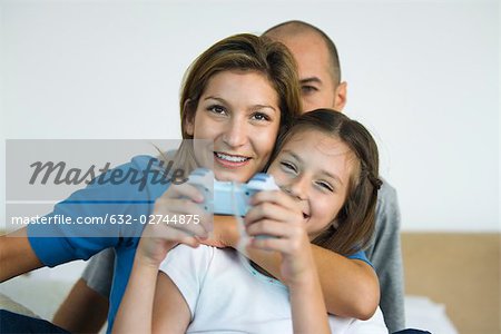 Girl playing video game, parents watching