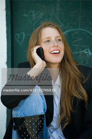 Young woman with strawberry blonde hair and freckles talking on cell phone, smiling
