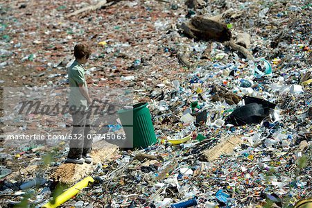 Boy picking up garbage in dump, high angle view