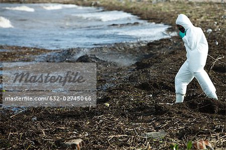 Person im Schutzanzug entlang verschmutzt Ufer