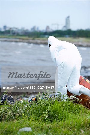 Person in protective suit cleaning up polluted shore