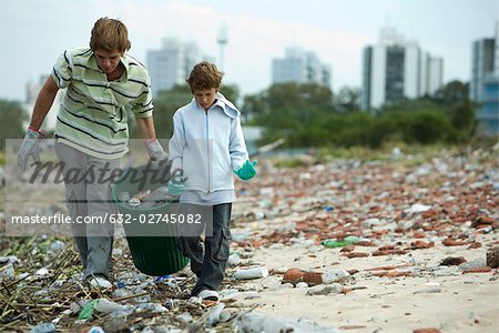 Jeune mâle et garçon collecte des matériaux recyclables en dépotoir