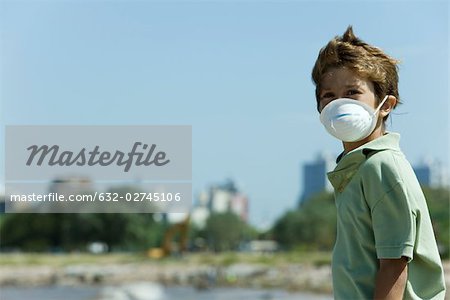 Garçon debout à l'extérieur, portant le masque de la pollution