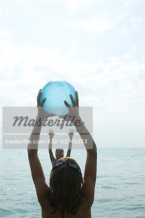 Adolescentes jouer avec le ballon de plage dans la mer