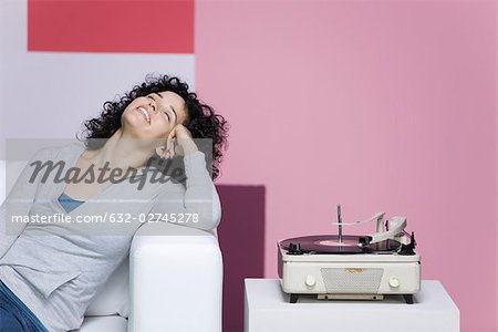 Woman enjoying music, listening to old-fashioned record player