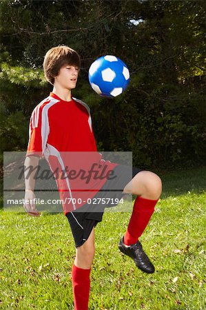 Teenage Boy Bouncing Soccer Ball on Knee