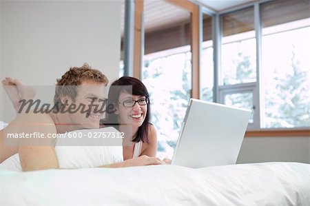 Couple au lit à l'aide d'ordinateur portable