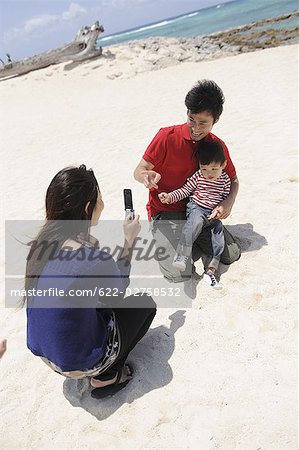 Mother taking snap of her family on beach