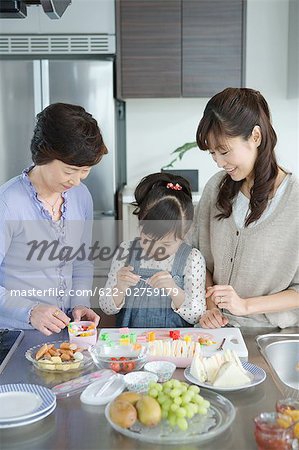 Jeune fille préparant le petit déjeuner avec sa mère et sa grand-mère