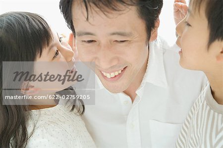 Son and daughter whispering in their father ears