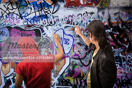 A young man and woman spraying graffiti