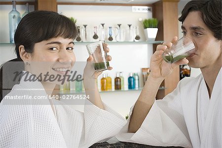 Portrait d'un jeune couple tenant des verres de jus d'agropyre