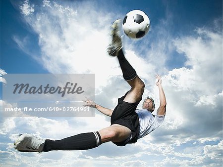 Joueur frappe le ballon pendant que silhouetté sur un ciel bleu nuageux