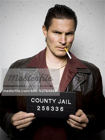 Mug shot of man with cigarette and gold chains