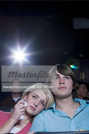 Crying girl and smiling boy watching movie at theater
